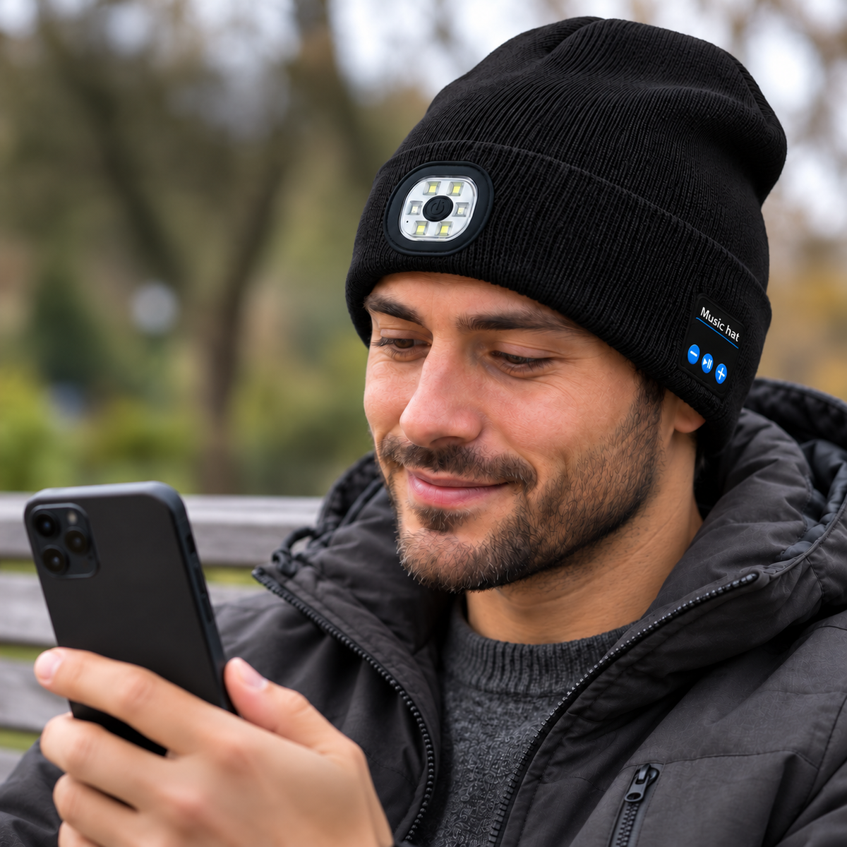 Adult wearing the black MITTSWELL Light & Sound Beanie while using a phone outdoors.
